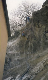 Concrete being projected from a cliff onto the back of a building  using acrobatic work methods