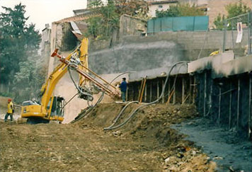 Excavacion e instalacion de bloques hormigon descendentes tras muro berlines, proyeccion de gunite, perforacion de anclajes y terraplenado