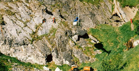 One team removes the equipment with the helicopter, the other fastens a load of explosives to the cliff face using acrobatic access work techniques